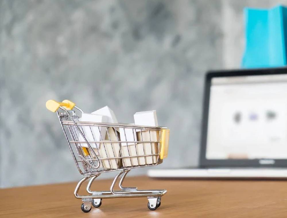 A small shopping cart in front of a laptop